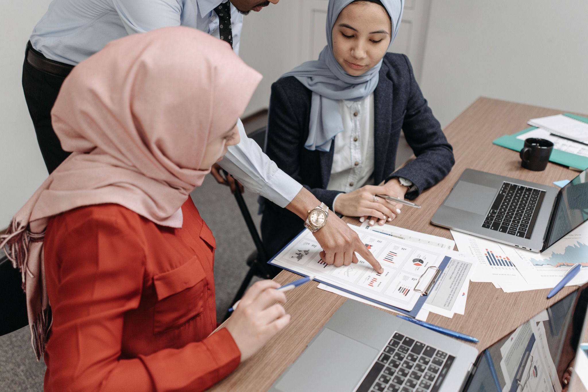 People collaborating over printed documents and technical work